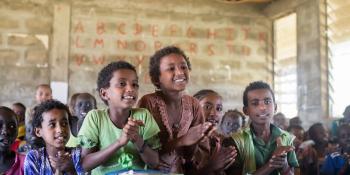 Ethiopian children sat in a class, smiling and clapping their hands