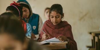 Little Sister Pramila writes in her exercise book in a classroom