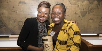 Emily Mabonga and Elisabeth Kisakye smile as they stand together and hold an award