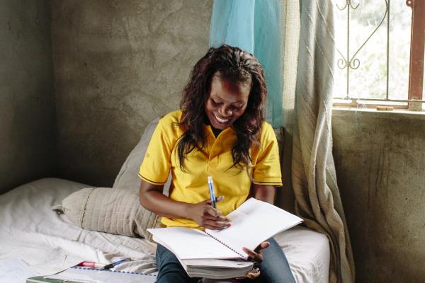 A young Mozambicuan woman sits on her bed to study