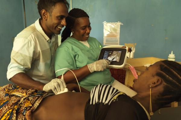 A male doctor and female midwife show a young pregnant woman her ultrasound scan