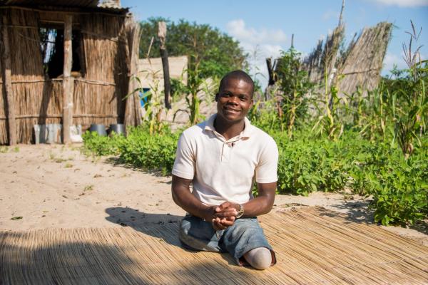 Faife Mufundisse sits on a straw mat outside a partially-destroyed house in Chimoio, Mozambique