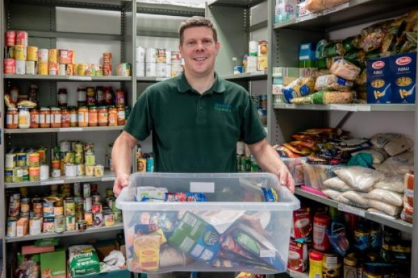 Man in foodbank holding donated items