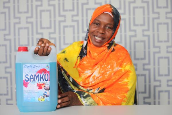 A woman smiles as she proudly shows a large bottle of liquid soap