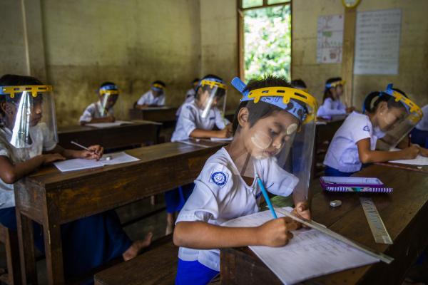 Children wear visors and study in a Burmese clasroom.