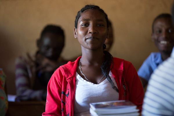 Zena Boko, Age 16, Grade 8, smiles sitting in class having returned to school.