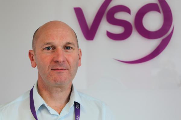 VSO Chief Executive Philip Goodwin in front of the VSO logo