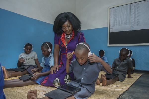 Teacher Grace monitors children using Unlocking Talent digital education technology