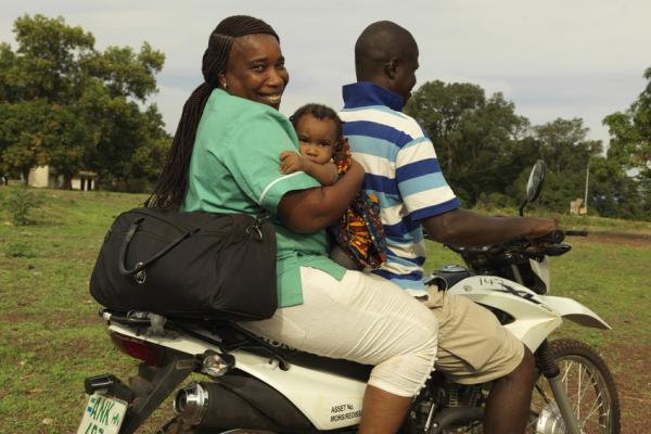 Midwife Catherine Swaray carries her own baby to work everyday on the back of a motor bike