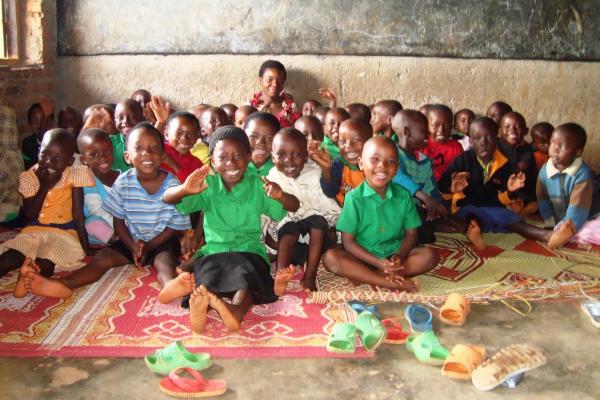 classroom of children sat on the floor smiling at the camera