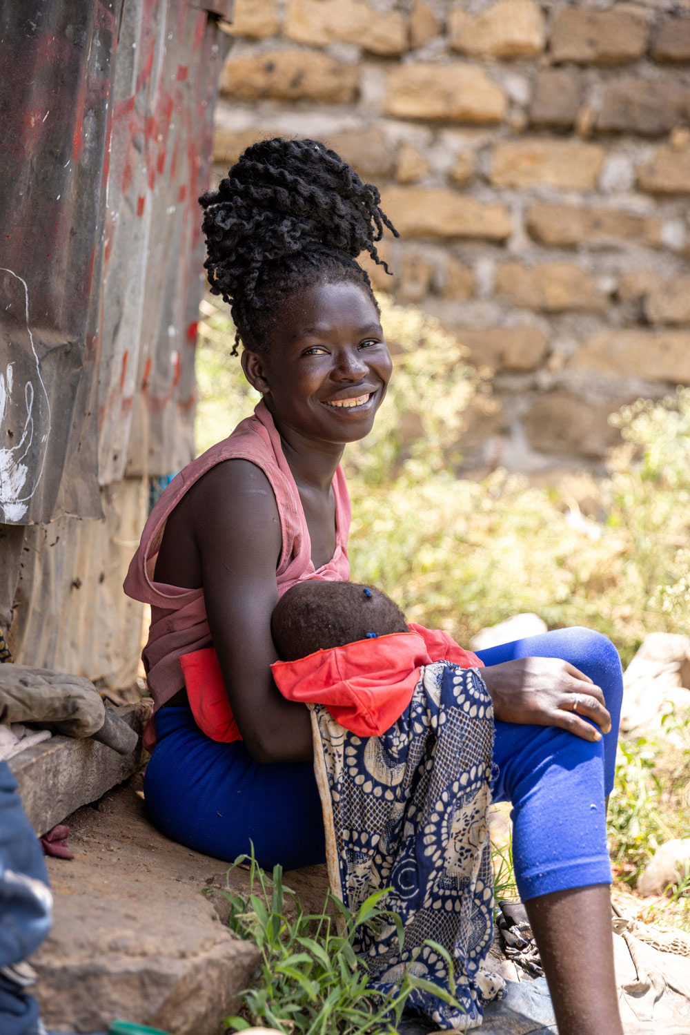 Doreen, waste picker with her baby outside her house