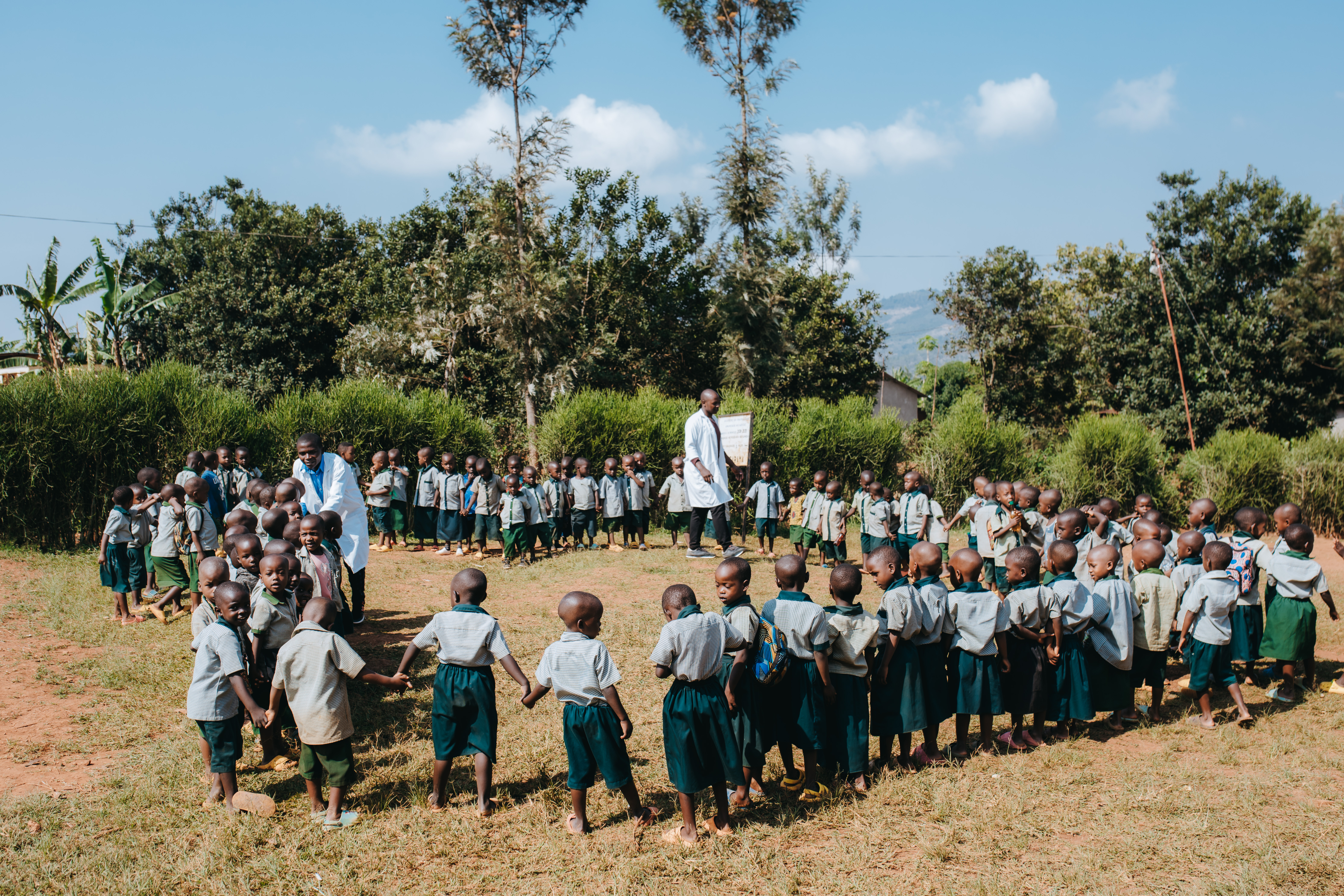 Teacher Olivier outside school with his students stood in a circle