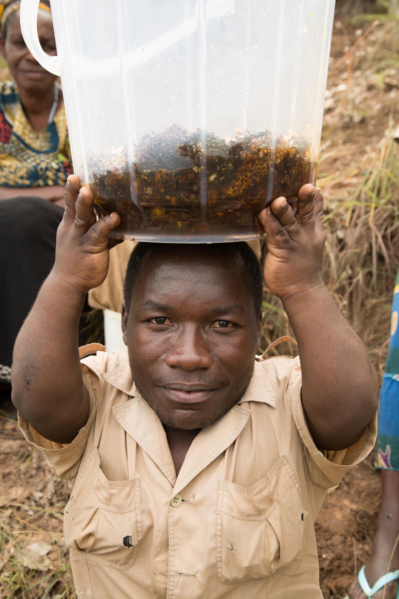 A disabled member of Shori village with a bucket of honey.