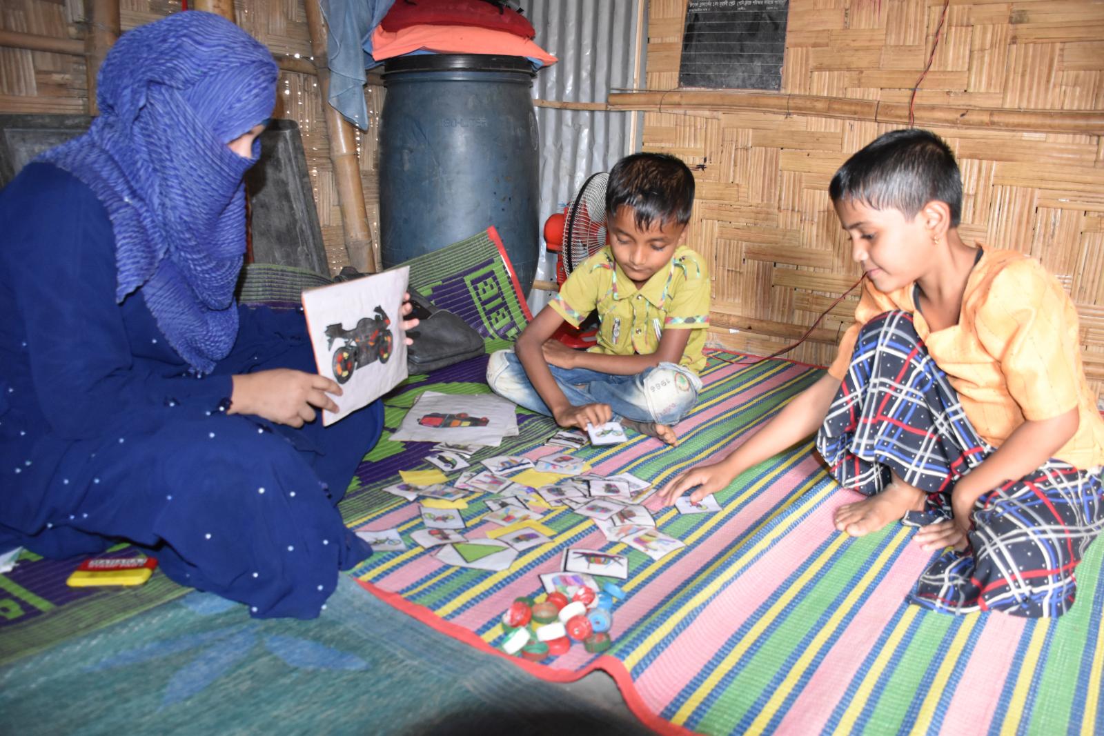 Big Sister Moreom playing a teaching game with two of her young students