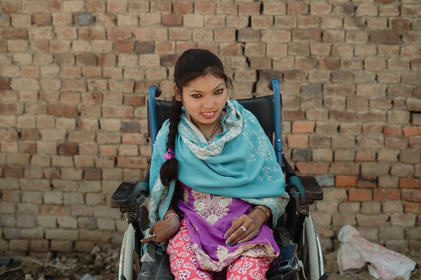 Rabina sitting in her wheelchair given to her by a VSO volunteer.