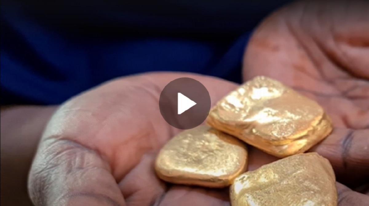 Hand holding nuggets of precious metal.