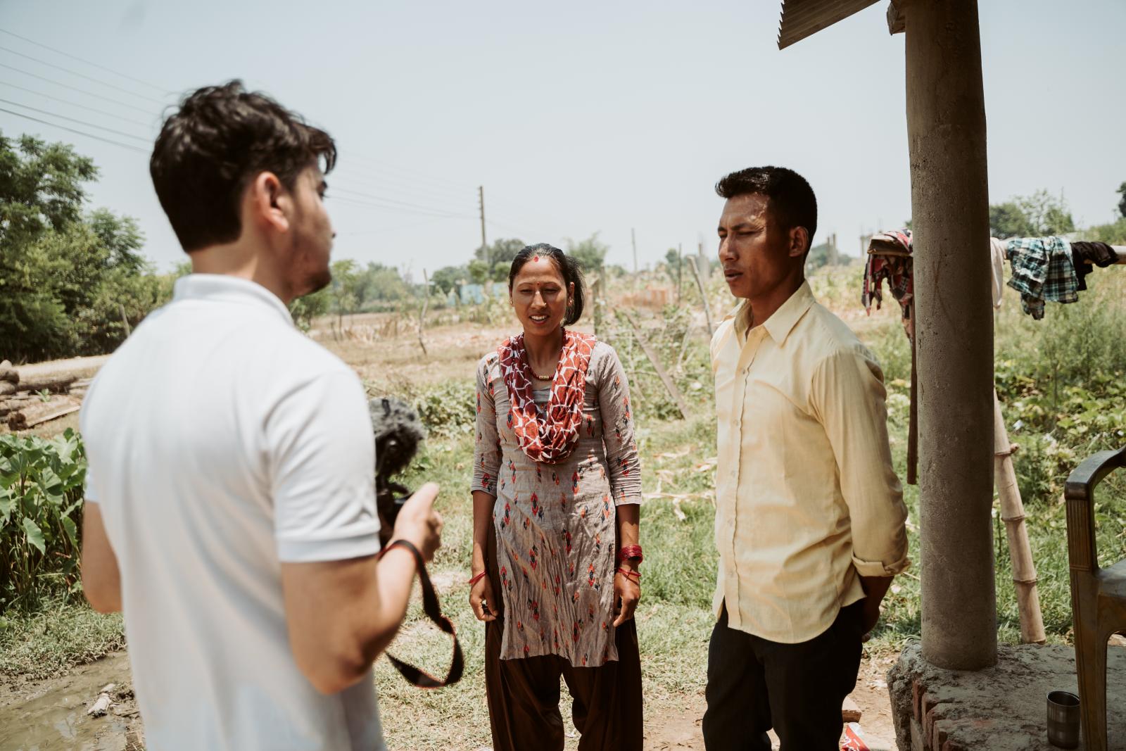 Volunteer Raj standing with a couple.