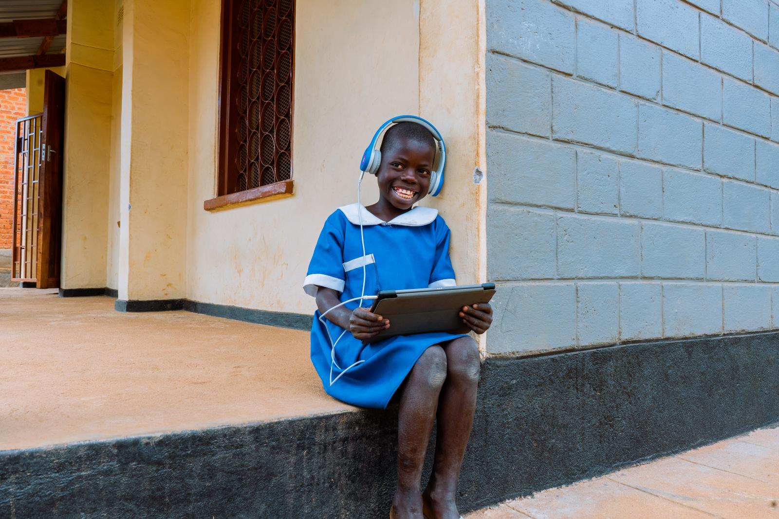 Smiling child sits on step with tablet