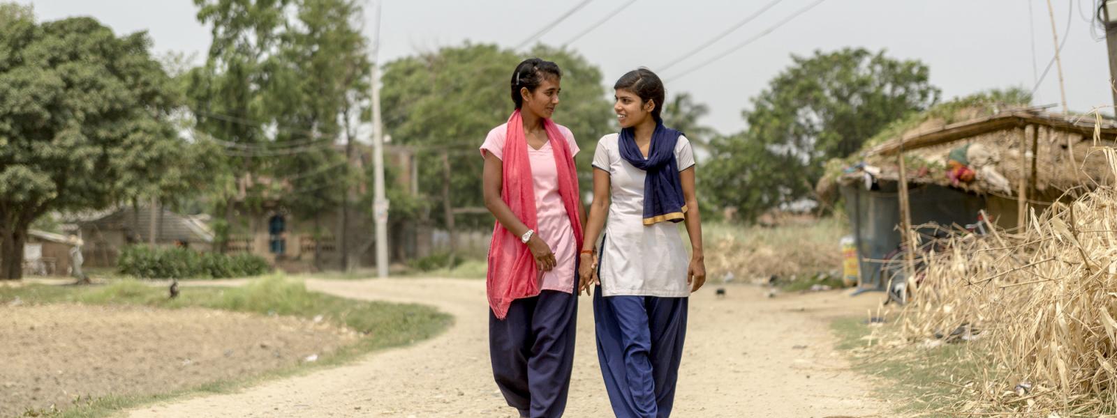 20-year-old "Big Sister" Seema walks with her "Little Sister," 15-years-old Pramila, towards Pramila's schoo