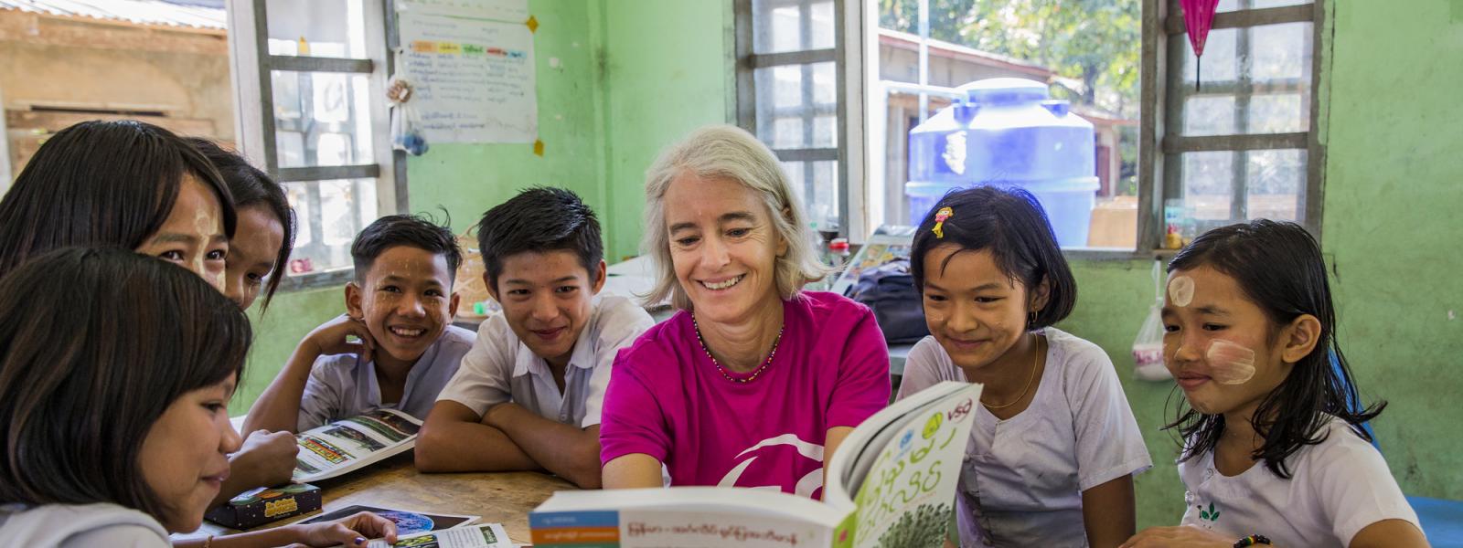 VSO Volunteer Ana Paula Pinto reads textbook and performs in classroom activity with the students from primary school at Kyakathone primary school, Myanmar