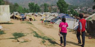Two people, one in a VSO t-shirt, survey a camp for internally displaced people
