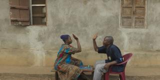 A married couple high five over a board game they are playing outside