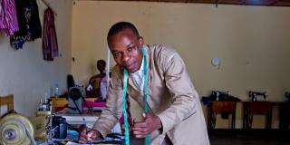 Tailor Rafiki Bienvenue goes over paperwork in his workshop