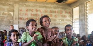 Children sing and clap happily in a busy classroom