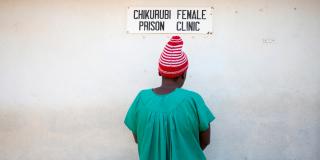 An inmate stands in front of a sign for Chikurubi female prison clinic