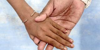 A man holds the hand of a young girl