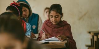 Little Sister Pramila writes in her exercise book in a classroom