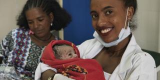 VSO-trained midwife Tsige holds a newborn baby whilst the mother, Mebrhit, rests