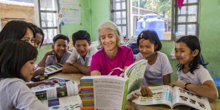 Volunteer Ana Paula Pinto sits and reads with children in Kyakathone primary school