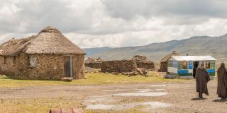 Landscape view of Lesotho, featuring traditional stone buildings in the foreground and mountains in the distance