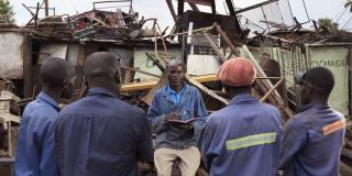 Peer educator Arthur instructs four other workmen in a junkyard