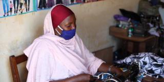 A woman using a sewing machine to make face masks