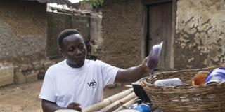 Community volunteer James Lansana puts dishes out to try on an outdoor bamboo rack