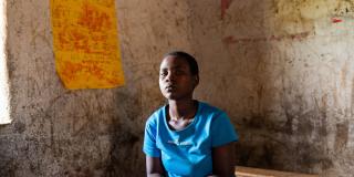 Student Elizabeth sits on a wooden bench in the classroom of the Nyamagenga catch-up centre