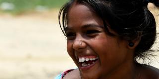 A young Nepali girl laughs as water droplets run down her chin