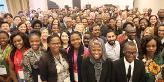 A large group of people stand together and smile for the camera, at the IVCO 2019 conference in Kigali