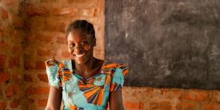 girl smiling in front of classroom chalkboard