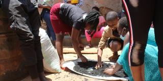 Women and youth making briquettes for fuel. Uganda.