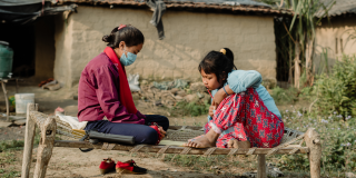 Two adolescent girls study on a bench