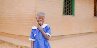 Student Alinafe stands and smiles outside her classroom