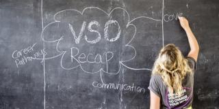 a VSO volunteer uses the blackboard in a classroom