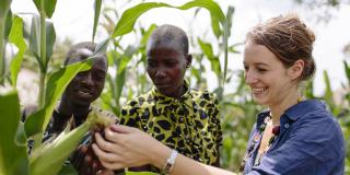 Randstad volunteer Jenny Hoevenagel looks at crops in a field next to members of a youth co-operative