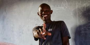 An ICS volunteer in front of a blackboard