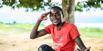 Alfred Kunda smiles and poses as he sits on the lake shore