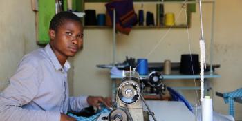 A young male tailor works at a sewing machine