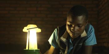 A child writing using a solar-powered lantern